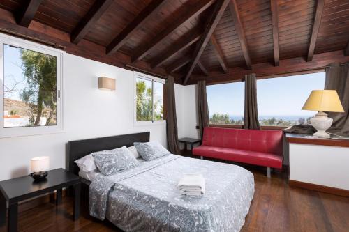 Un dormitorio con una cama y una silla roja. en Home2Book Ocean Surf House Fuerteventura, en La Oliva