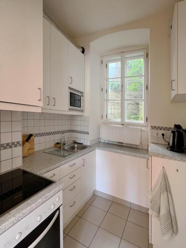 cocina con armarios blancos, fregadero y ventana en Ferienwohnung Sterngasse en Melk