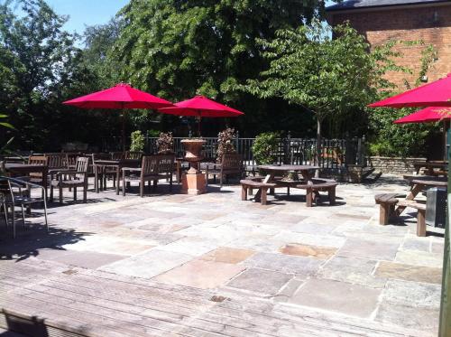 a patio with tables and benches with red umbrellas at The Admiral Hornblower in Oakham