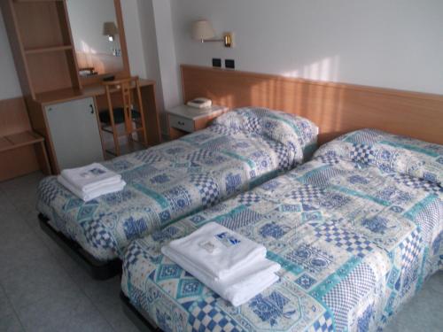 two beds in a hotel room with towels on them at Scacco Rosso in SantʼEgidio alla Vibrata