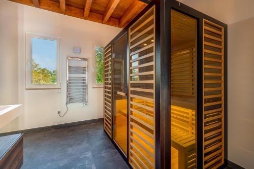 a bathroom with a shower with wooden cabinets and a window at Meia Lua - Deluxe countryside villa with pool and sea views near Barril beach, Tavira in Luz de Tavira