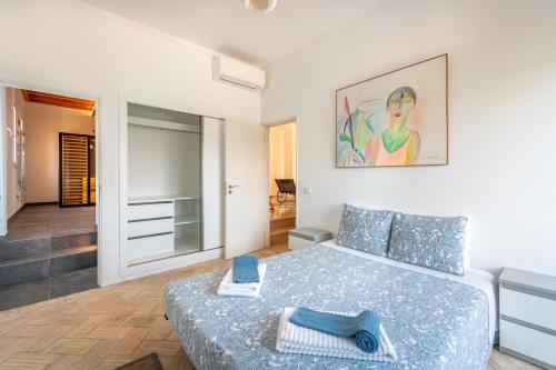 a bedroom with a large bed with blue sheets and a painting at Meia Lua - Deluxe countryside villa with pool and sea views near Barril beach, Tavira in Luz de Tavira