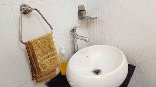 a bathroom with a white sink and aige towel at Gaurang Homestay in Vadodara