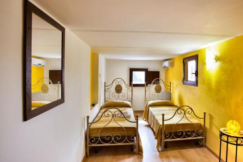 CollepassoにあるB&B Perla del Sudの黄色い壁の客室内のベッド2台