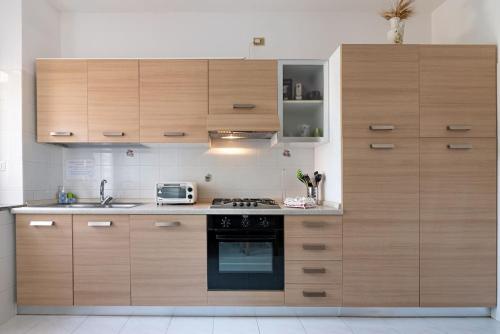 a kitchen with wooden cabinets and a stove top oven at La Lampara - Casa Panoramica 4 Km dalla Pelosa in Stintino