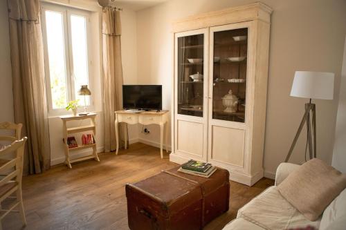 un salon avec une grande armoire blanche et une télévision dans l'établissement La maison du bassin, à LʼIsle-sur-la-Sorgue