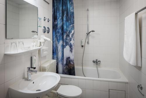 a bathroom with a sink and a toilet and a tub at Ariva Boardinghouse Platanenhof in Mannheim