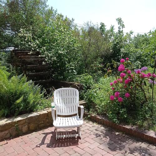 a white chair sitting on a brick patio with flowers at Le gîte de l'AA in Renty