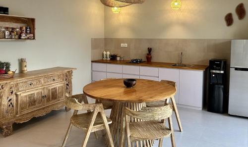 a kitchen with a wooden table and a refrigerator at Pandan Villas in Selong Belanak