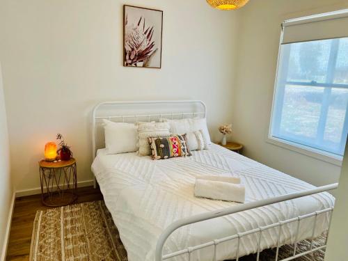 a white bed in a room with a window at Bluebird Days - Pet Friendly in Robe