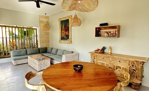 un soggiorno con tavolo in legno e divano di Pandan Villas a Selong Belanak