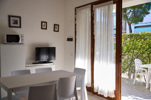a dining room with a table and chairs and a television at Appartamenti Villa Paola-Pochi passi dal mare-Zona piazza Aurora-Lido di Jesolo in Lido di Jesolo