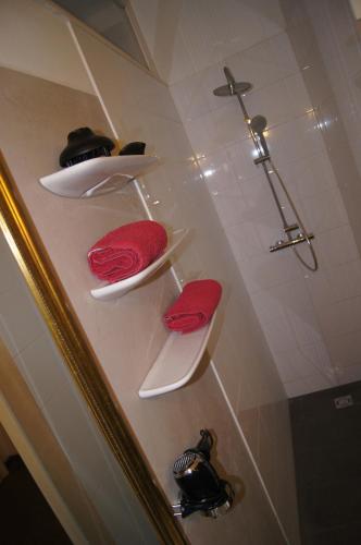a bathroom with white shelves with red towels and a shower at Altstadthaus Cityappartements in Graz