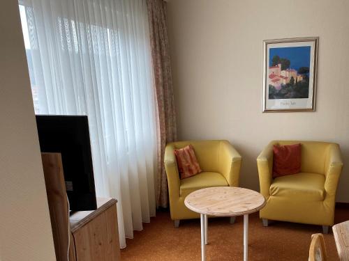 a living room with two chairs and a table and a tv at Wellnesshotel Rothfuß mit Spa und 2 Schwimmbädern in Bad Wildbad