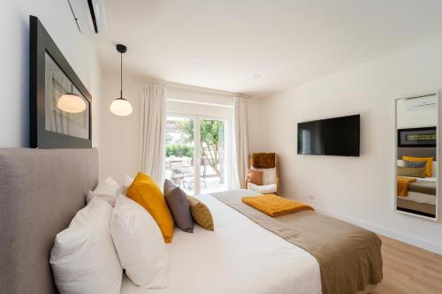 a bedroom with a large white bed with yellow pillows at Villa Shaz Cascais in Cascais