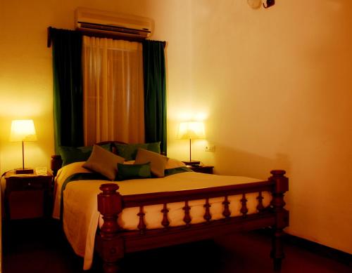 a bedroom with a bed with a window and two lamps at Maison Perumal Pondicherry - A CGH Earth Experience in Puducherry