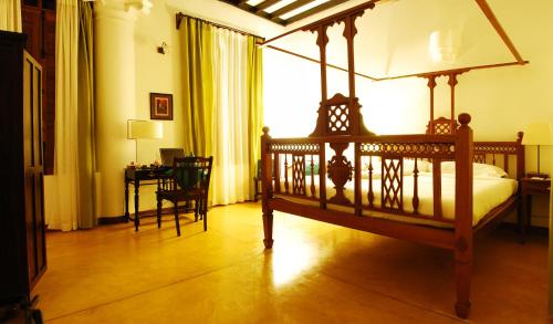 a bedroom with a bed and a desk and a window at Maison Perumal Pondicherry - A CGH Earth Experience in Puducherry