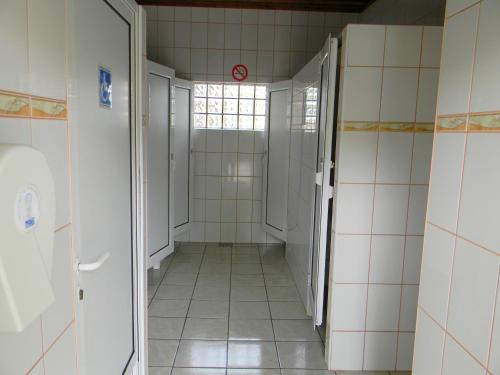 a hallway of a bathroom with white tiled walls at Camping Eldorado in Gilău