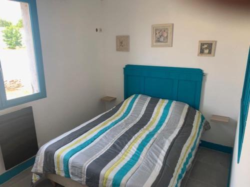 a small bedroom with a bed with a striped blanket at LE DEPOT appartement du port à Champvert in Champvert