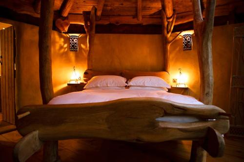 a bedroom with a wooden bed with two lamps at Little Hollows Glamping in Little Malvern