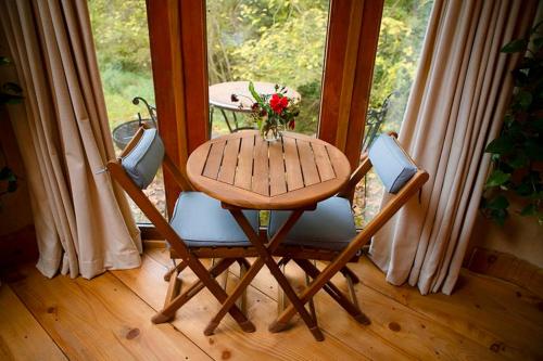a wooden table and two chairs with a table and flowers at Little Hollows Glamping in Little Malvern
