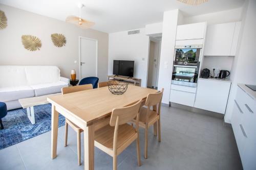 Il dispose d'une cuisine et d'un salon avec une table et des chaises en bois. dans l'établissement Les Terrasses De Forville by Connexion, à Cannes