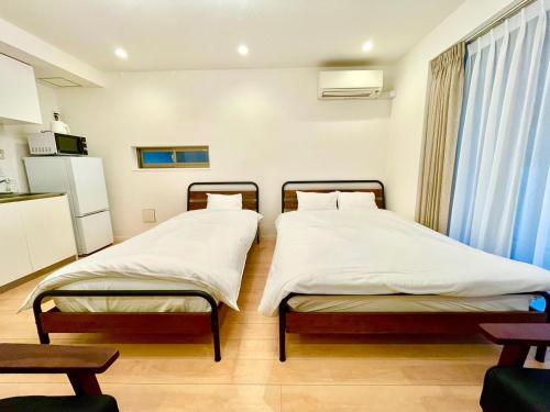 two twin beds in a room with a kitchen at SALON渋谷4B in Tokyo