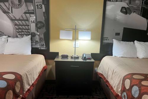 a hotel room with two beds and a cross on a desk at Super 8 by Wyndham Pasadena in Pasadena
