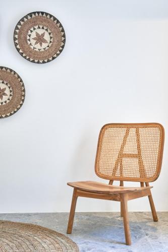a rattan chair and a table in front of a wall at Ubud Mykonos in Agios Ioannis Mykonos