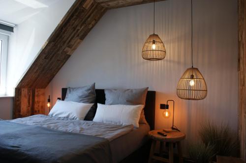 1 dormitorio con 1 cama y 2 luces colgantes en Dock2Apartment Rügen Whg 3 großer Balkon, ruhige Lage, en Lohme