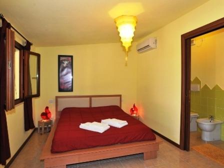 a bedroom with a red bed and a bathroom at Butterfly House Bed & Breakfast in Alghero