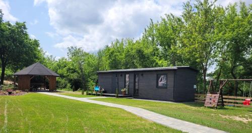 a small black cabin with a path leading to it at DomEK Obok Rzeki in Bałtów
