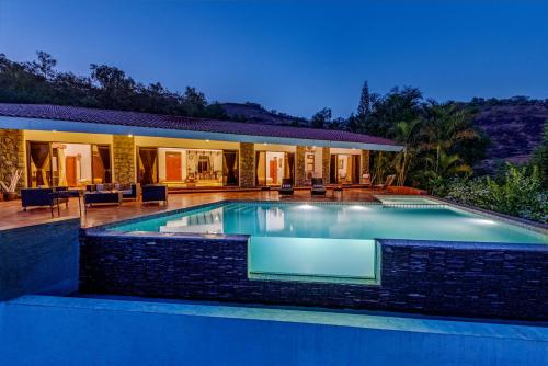 a swimming pool in front of a house at SaffronStays Shambhala Lakeside-Infinity Pool Villa in Pawna in Malavli
