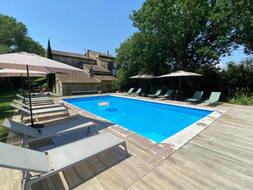 una piscina con tumbonas y sombrillas en Le Moulin de Montségur, en Montségur-sur-Lauzon