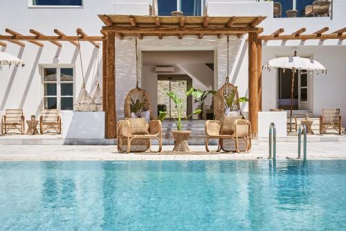 a pool with chairs and umbrellas next to a house at Ubud Mykonos in Agios Ioannis Mykonos