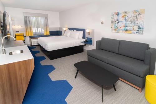 a hotel room with a bed and a couch at Microtel Inn & Suites by Wyndham Macedon in Macedon