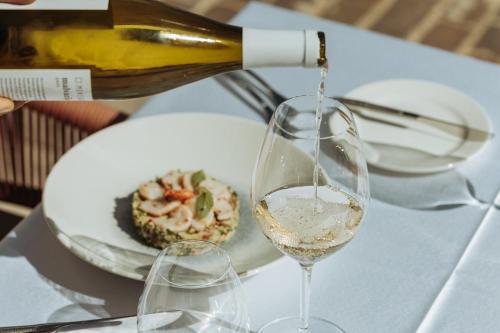 een fles witte wijn die in een wijnglas wordt gegoten bij Portonovi Resort in Herceg-Novi