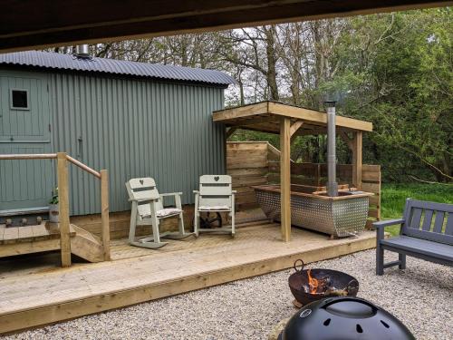 a deck with a gazebo and chairs and a grill at Hut In The Glade, Shepherds Hut with Hot Tub in Fryup