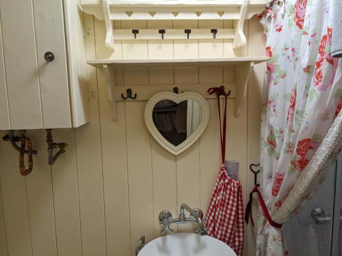 uma casa de banho com um espelho em forma de coração e um lavatório em Shepherds Hut with Hot Tub em Fryup