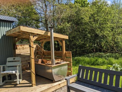 a wooden gazebo on a wooden deck with a bench at Hut In The Glade, Shepherds Hut with Hot Tub in Fryup