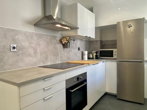 une cuisine avec des armoires blanches et un réfrigérateur en acier inoxydable dans l'établissement Suite Gloria Five stars holiday house, à Nice
