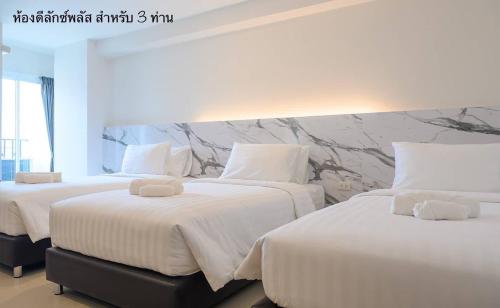 two beds in a hotel room with white sheets at Donmueang Place Hotel - SHA Plus in Bangkok