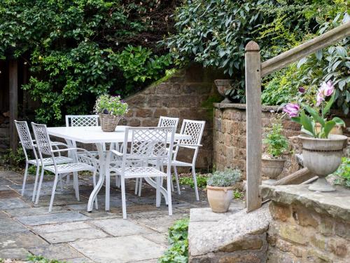 a white table and chairs in a garden at Thatch on the Green in Great Tew