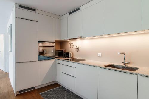 a kitchen with white cabinets and a sink at Linda Terrace by Quokka 360 - modern one-bedroom flat with sun terrace in Locarno
