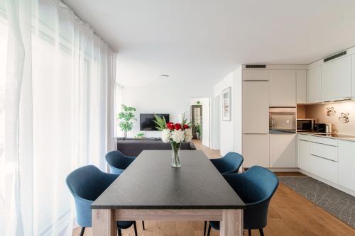 a dining room table with blue chairs and a vase of flowers at Linda Terrace by Quokka 360 - modern one-bedroom flat with sun terrace in Locarno