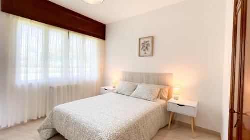 een witte slaapkamer met een bed en twee nachtkastjes bij Playa de Perbes - Casa con precioso jardín in Boebre