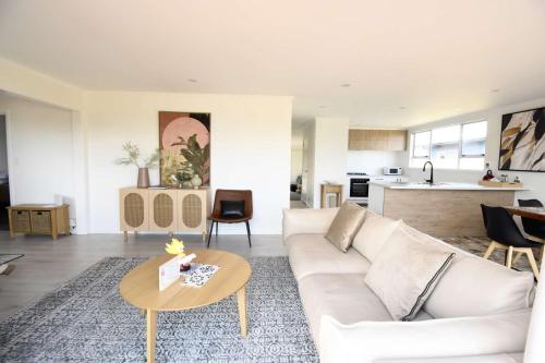 uma sala de estar com um sofá branco e uma mesa em Premium Comfortable Lake View 2BR em Taupo