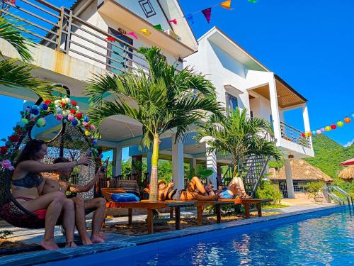 grupa osób siedzących przy basenie w ośrodku w obiekcie YoLo Pool Bar Villas w mieście Phong Nha