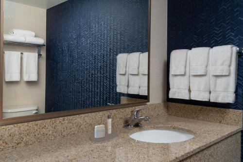 a bathroom with a sink and a mirror and towels at Fairfield by Marriott Fort Walton Beach-Eglin AFB in Shalimar