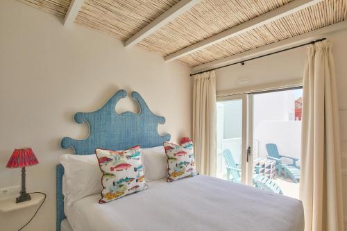 1 dormitorio con 1 cama con cabecero azul y ventana en El Escondite Tarifa, en Tarifa